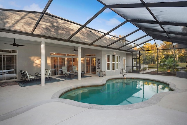 view of swimming pool with glass enclosure, ceiling fan, and a patio area