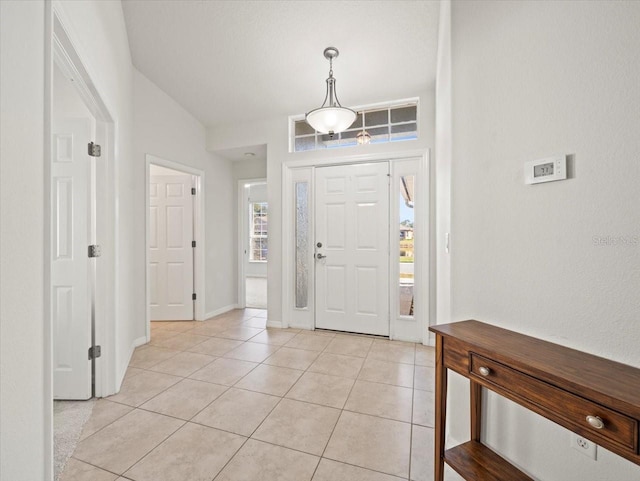 foyer with light tile patterned flooring, a healthy amount of sunlight, and lofted ceiling