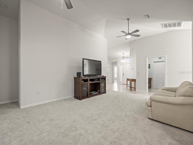 carpeted living room featuring ceiling fan with notable chandelier and high vaulted ceiling