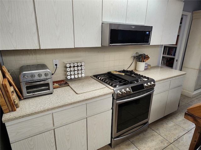 kitchen featuring decorative backsplash, light tile patterned flooring, and stainless steel range with gas stovetop