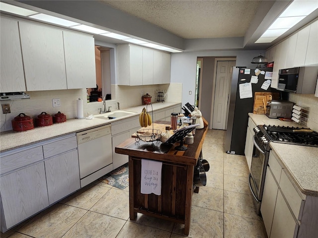 kitchen with dishwasher, backsplash, white cabinets, sink, and range with gas stovetop