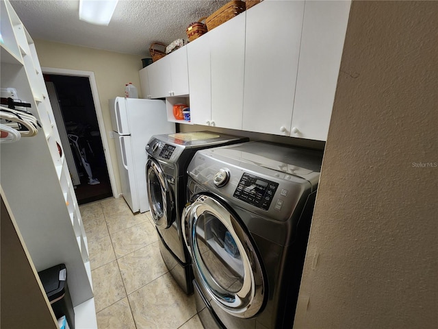 washroom featuring washer and clothes dryer, light tile patterned floors, cabinets, and a textured ceiling