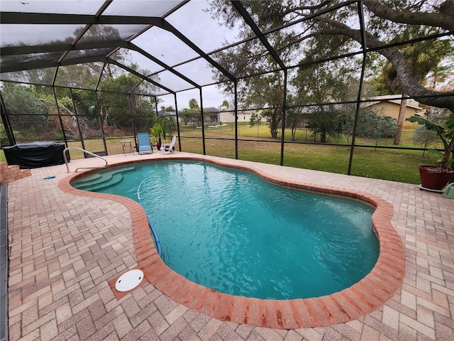 view of pool with a yard, glass enclosure, and a patio area