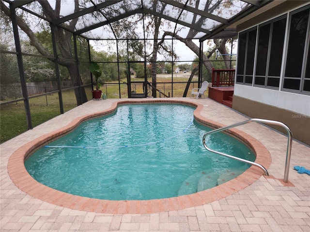 view of pool with glass enclosure and a patio