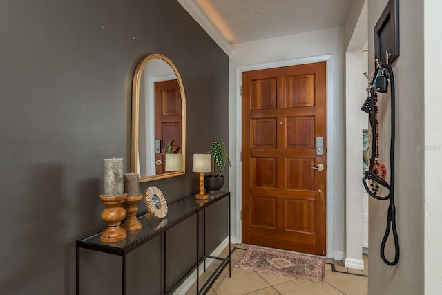 tiled foyer entrance featuring a textured ceiling and ornamental molding