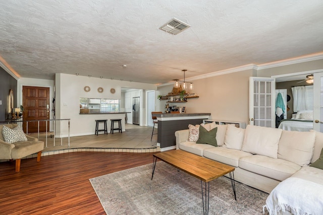 living room featuring ceiling fan, ornamental molding, a textured ceiling, and hardwood / wood-style flooring