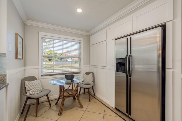 interior space with white cabinets, stainless steel fridge with ice dispenser, light tile patterned floors, and crown molding