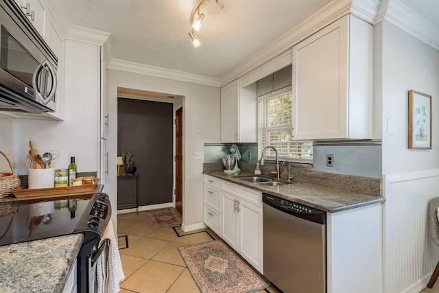 kitchen featuring appliances with stainless steel finishes, white cabinetry, dark stone countertops, and sink