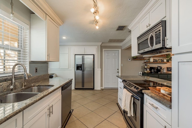 kitchen with appliances with stainless steel finishes, crown molding, sink, light tile patterned floors, and stone countertops