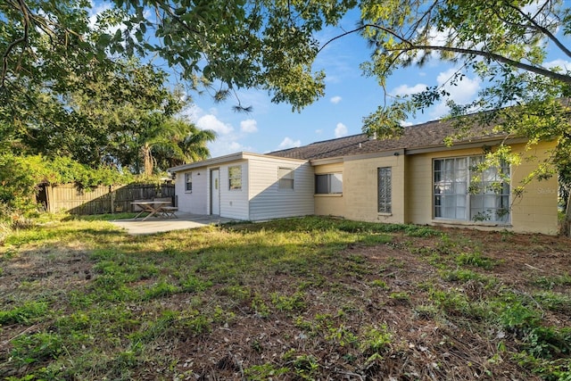 rear view of house featuring a lawn and a patio