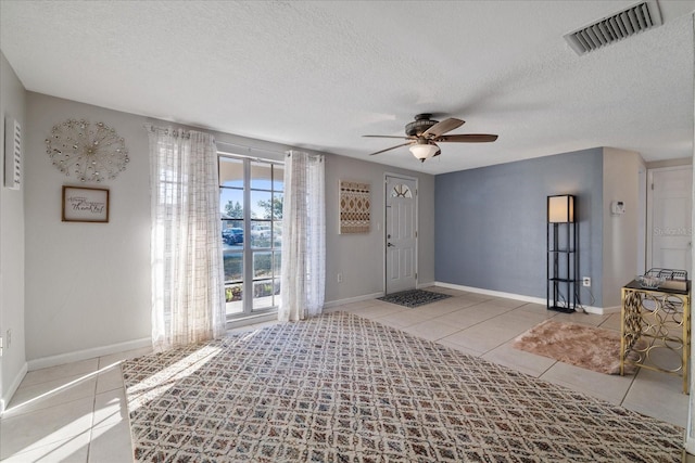 foyer entrance with ceiling fan, light tile patterned floors, and a textured ceiling