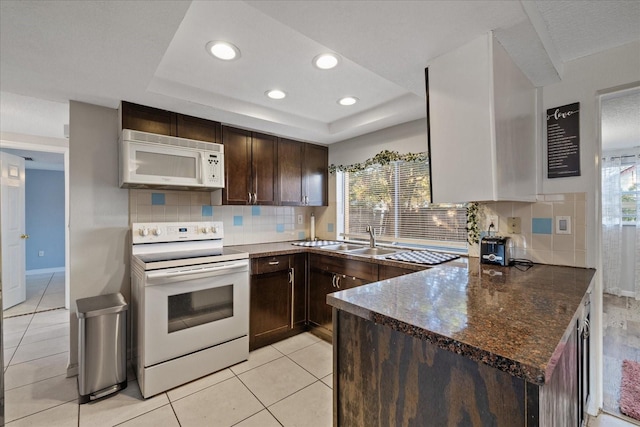 kitchen featuring light tile patterned flooring, white appliances, a raised ceiling, and sink