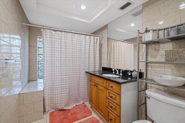 bathroom featuring tile patterned flooring, vanity, toilet, and tile walls