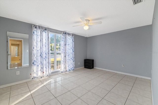 tiled spare room with a wealth of natural light and ceiling fan