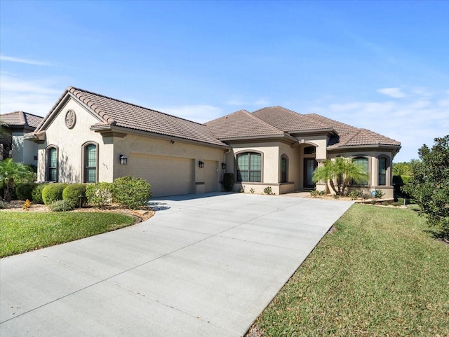 mediterranean / spanish house featuring a garage and a front lawn