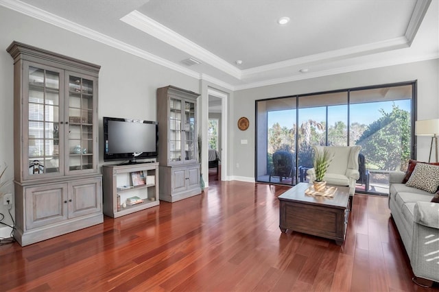 living room with a tray ceiling, dark hardwood / wood-style floors, and ornamental molding