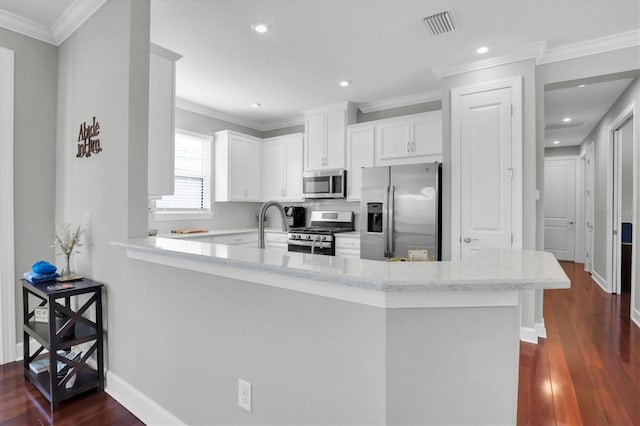 kitchen featuring white cabinetry, ornamental molding, dark hardwood / wood-style floors, kitchen peninsula, and stainless steel appliances