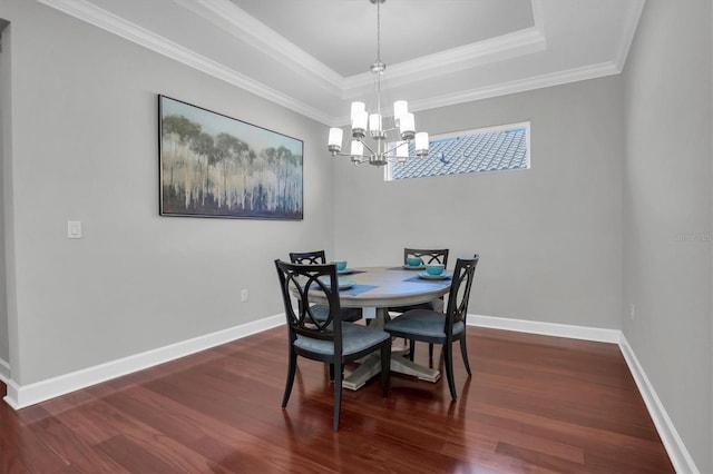 dining room featuring crown molding, dark wood-type flooring, an inviting chandelier, and a tray ceiling