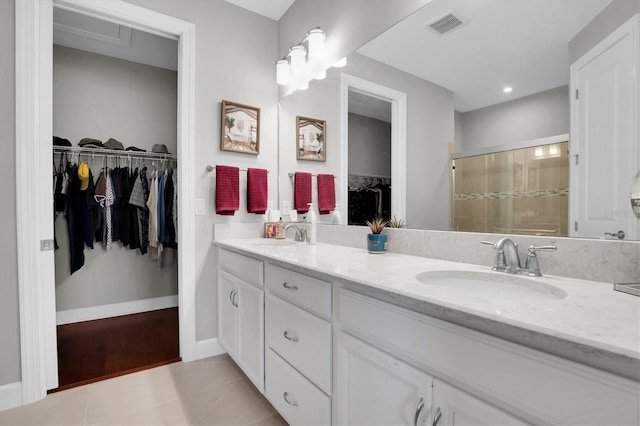 full bath featuring a sink, visible vents, a stall shower, and a walk in closet