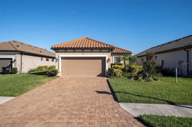 mediterranean / spanish-style home featuring an attached garage, stucco siding, a front lawn, a tile roof, and decorative driveway