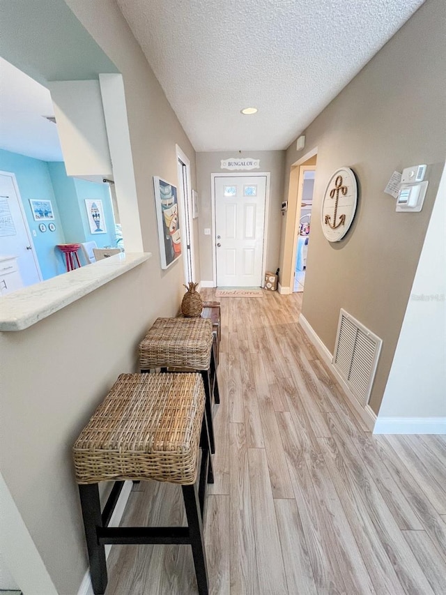 foyer entrance with light wood-type flooring and a textured ceiling