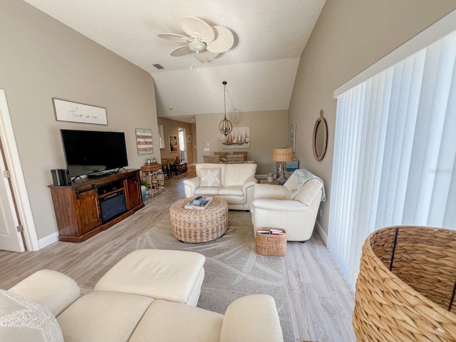 living room featuring ceiling fan, light hardwood / wood-style flooring, and vaulted ceiling