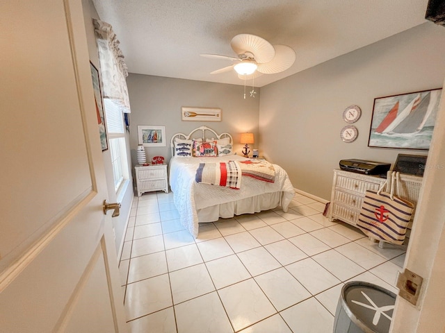 bedroom featuring ceiling fan, light tile patterned flooring, and a textured ceiling