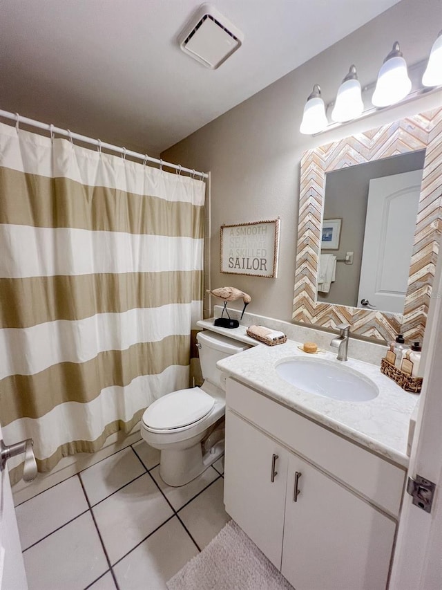 bathroom with toilet, vanity, and tile patterned floors