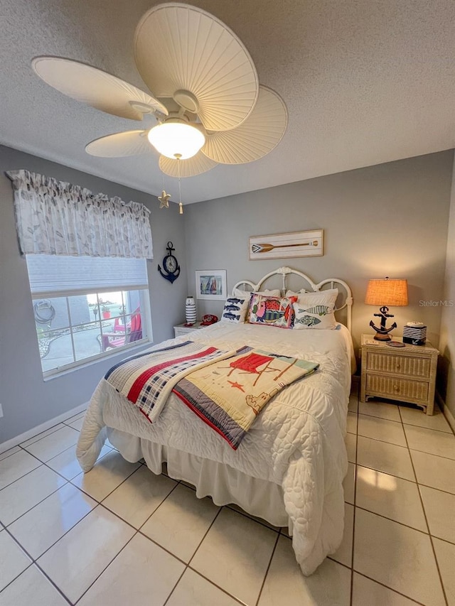 bedroom featuring ceiling fan, light tile patterned floors, and a textured ceiling