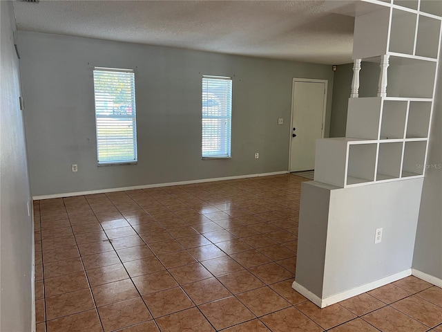 tiled empty room with a textured ceiling