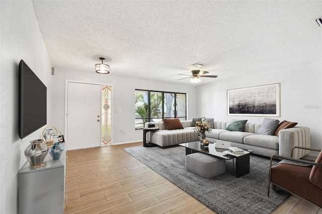 living room with ceiling fan and a textured ceiling