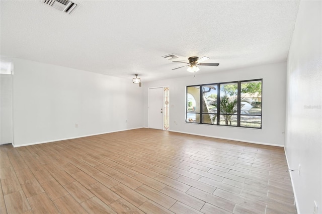 empty room with ceiling fan and a textured ceiling