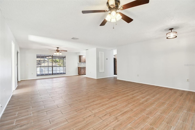 unfurnished living room featuring ceiling fan and a textured ceiling