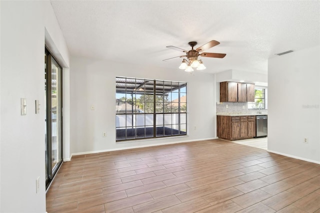 unfurnished living room with ceiling fan and a textured ceiling