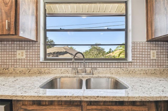 kitchen featuring a healthy amount of sunlight, light stone counters, and sink