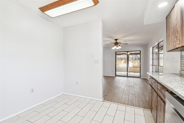 kitchen with light stone countertops, stainless steel dishwasher, and ceiling fan