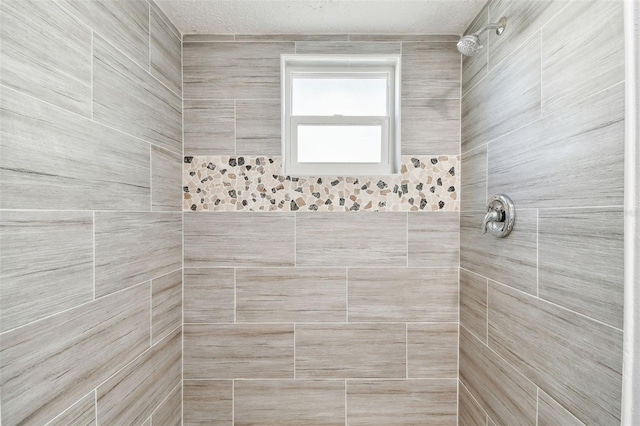 bathroom with a tile shower and a textured ceiling