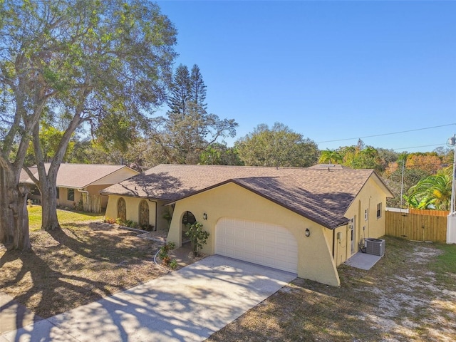 ranch-style house with central air condition unit and a garage