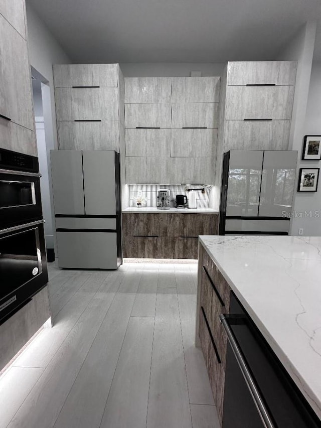 kitchen with multiple ovens, light stone counters, and white refrigerator