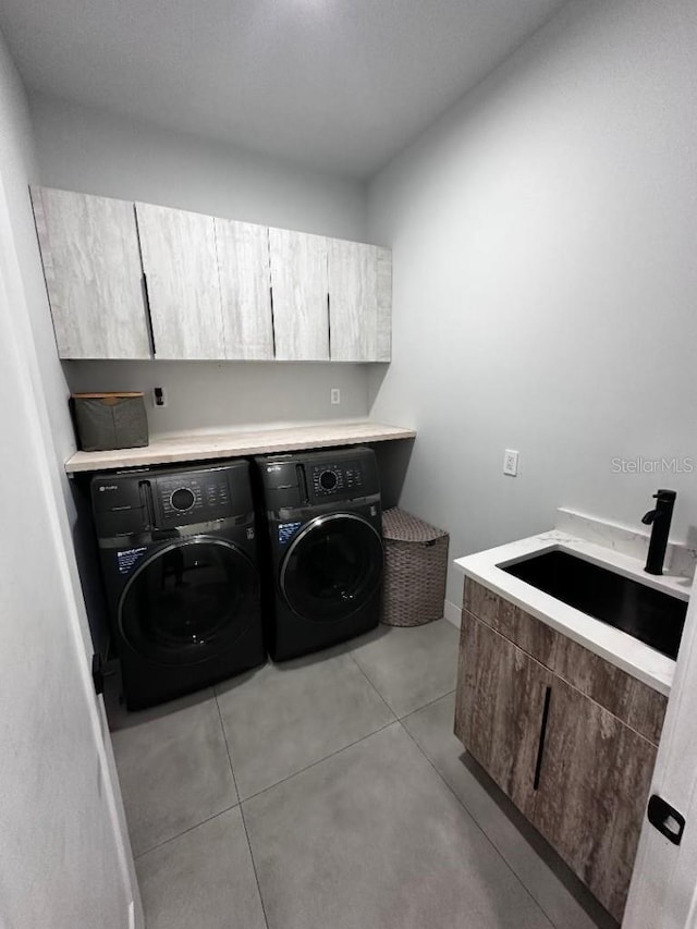 clothes washing area featuring washer and clothes dryer, light tile patterned flooring, cabinets, and sink