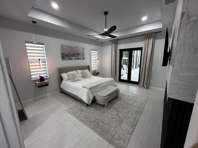 bedroom featuring access to outside, french doors, a raised ceiling, ceiling fan, and light wood-type flooring