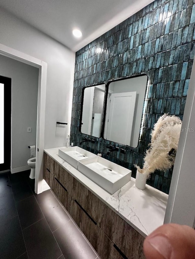 bathroom featuring tile patterned flooring, vanity, tile walls, and toilet