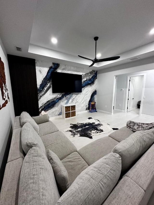 living room featuring a raised ceiling and ceiling fan