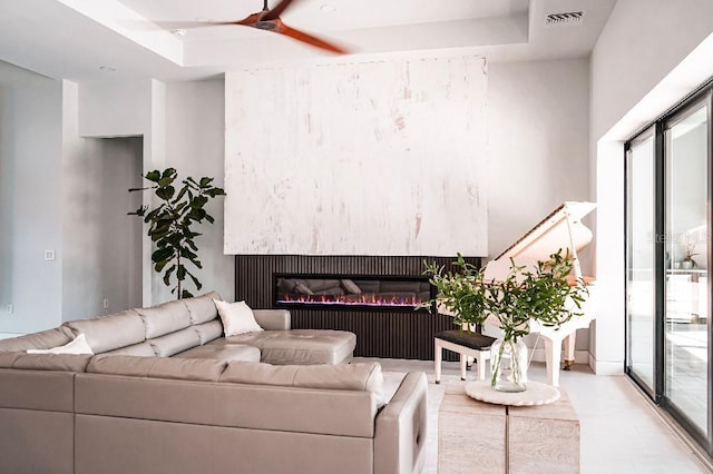 living area featuring a raised ceiling, visible vents, ceiling fan, and a premium fireplace