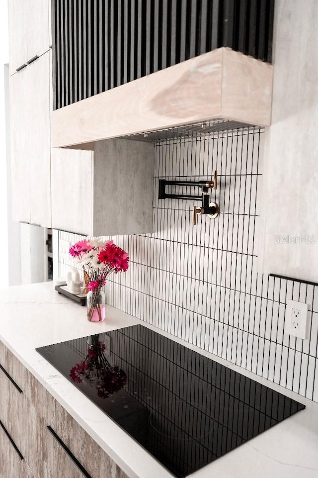 interior space with under cabinet range hood, modern cabinets, and black electric cooktop