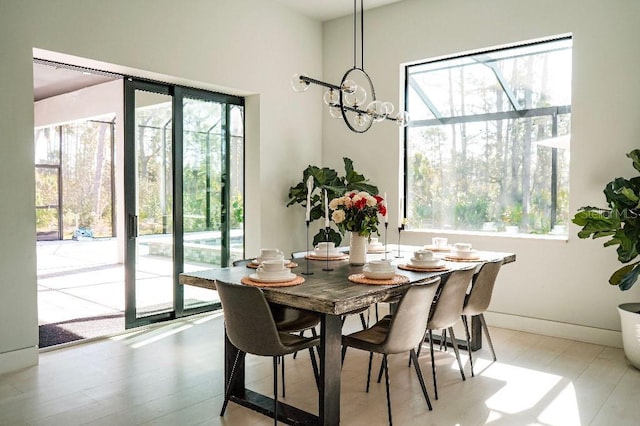 dining room featuring a chandelier, light wood-type flooring, and baseboards