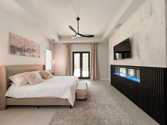 bedroom with visible vents, a raised ceiling, a ceiling fan, access to exterior, and a multi sided fireplace