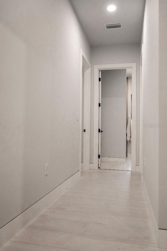 corridor featuring light wood-type flooring and visible vents