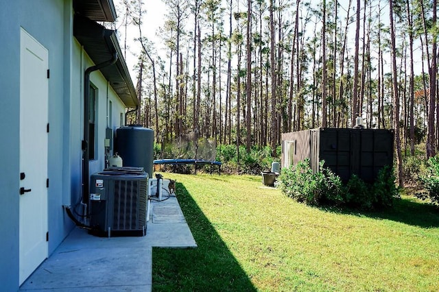 view of yard with a trampoline and central air condition unit