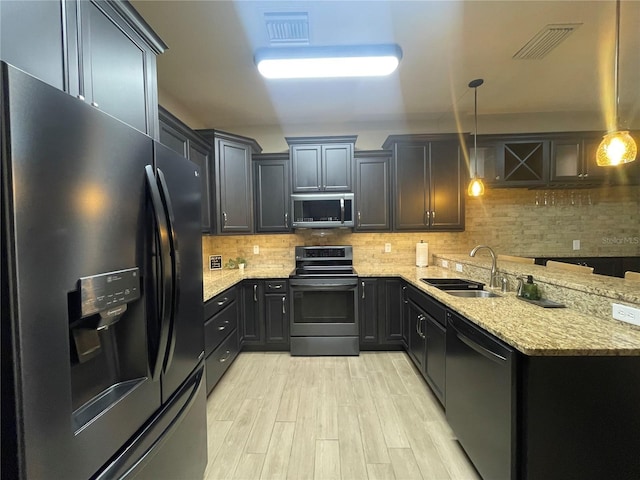 kitchen with backsplash, black appliances, sink, light stone countertops, and decorative light fixtures